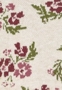 Tela de punto con fondo crema que presenta un patrón floral de flores rojas y rosas con hojas verdes.