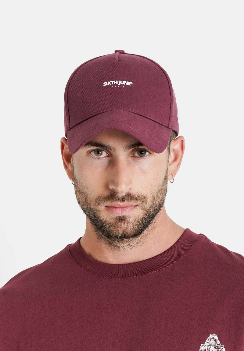 Gorra burdeos hecha de mezcla de algodón, con visera curva y logo bordado en la parte frontal. Textura suave con parte trasera ajustable.