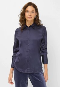 Navyblaue Satin-Schrift mit einem Umlegekragen, durchgehender Knopfleiste und langen Ärmeln, die eine glatte Textur und einen abgerundeten Saum aufweist.