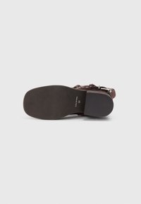 Scarpa in pelle marrone con una texture liscia, punta arrotondata e suola piatta. Presenta dettagli con il marchio e una misura di 37.
