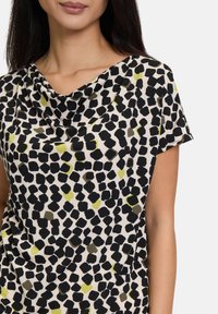 Cowlneck top van lichtgewicht stof, met een zwart, groen en beige abstract patroon, korte mouwen en een ontspannen pasvorm.