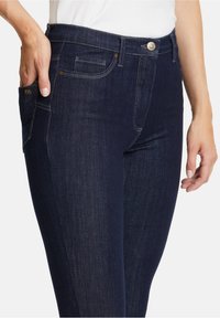 Jeans in denim blu scuro con vestibilità slim, dotati di tasche frontali, cuciture discrete e chiusura con bottone metallico in vita.