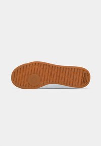 Sola de sapato com piso de borracha castanha apresentando padrões retangulares, design circular perto do calcanhar e logotipo da Reebok perto da área dos dedos.