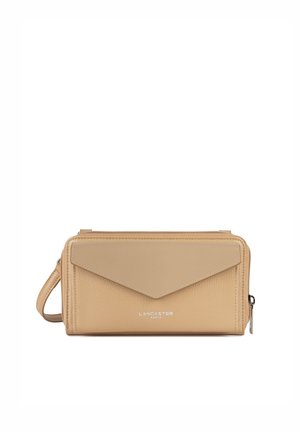 Sac bandoulière en cuir beige avec une finition texturée, un design de rabat géométrique et un logo en argent. Comprend une bandoulière amovible et une fermeture éclair.