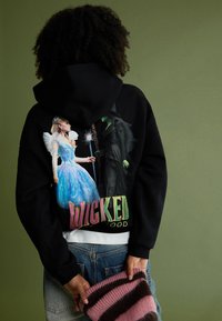 Czarna Bluza z kapturem z kolorową grafiką przedstawiającą dwie postacie, jedna w niebieskiej sukience, a druga w czarnym stroju, z napisem "Wicked Good."