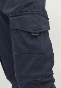 Pantalons cargo bleu marine avec une poche latérale, coutures piquées, texture lisse et design fuselé pour la fonctionnalité et l'ajustement.