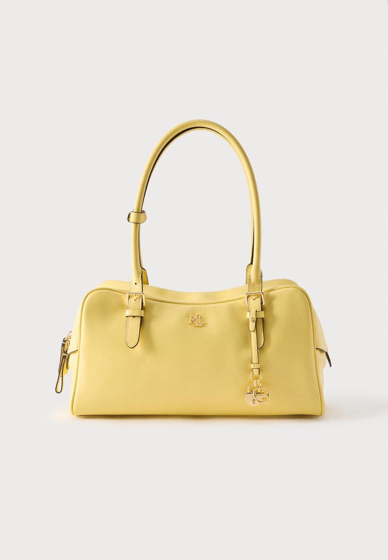 Κίτρινη δερμάτινη τσάντα χειρός με διπλούς ρυθμιζόμενους ιμάντες ώμου, λογότυπο σε χρυσό τόνο και διακοσμητικό μπρελόκ με λουκέτο μπροστά.