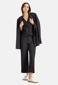 Charcoal gray three-piece suit with a tailored jacket, vest, and wide-leg trousers. Designed with a textured fabric and matching buttons.