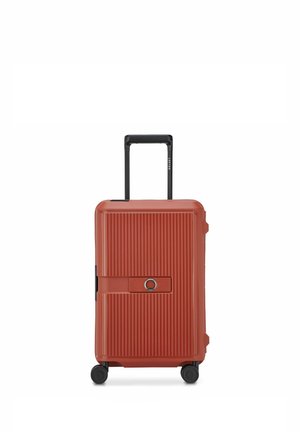 Maleta rígida roja con superficie estriada, cerradura de combinación incorporada, asa negra retráctil y cuatro ruedas giratorias sobre fondo blanco.