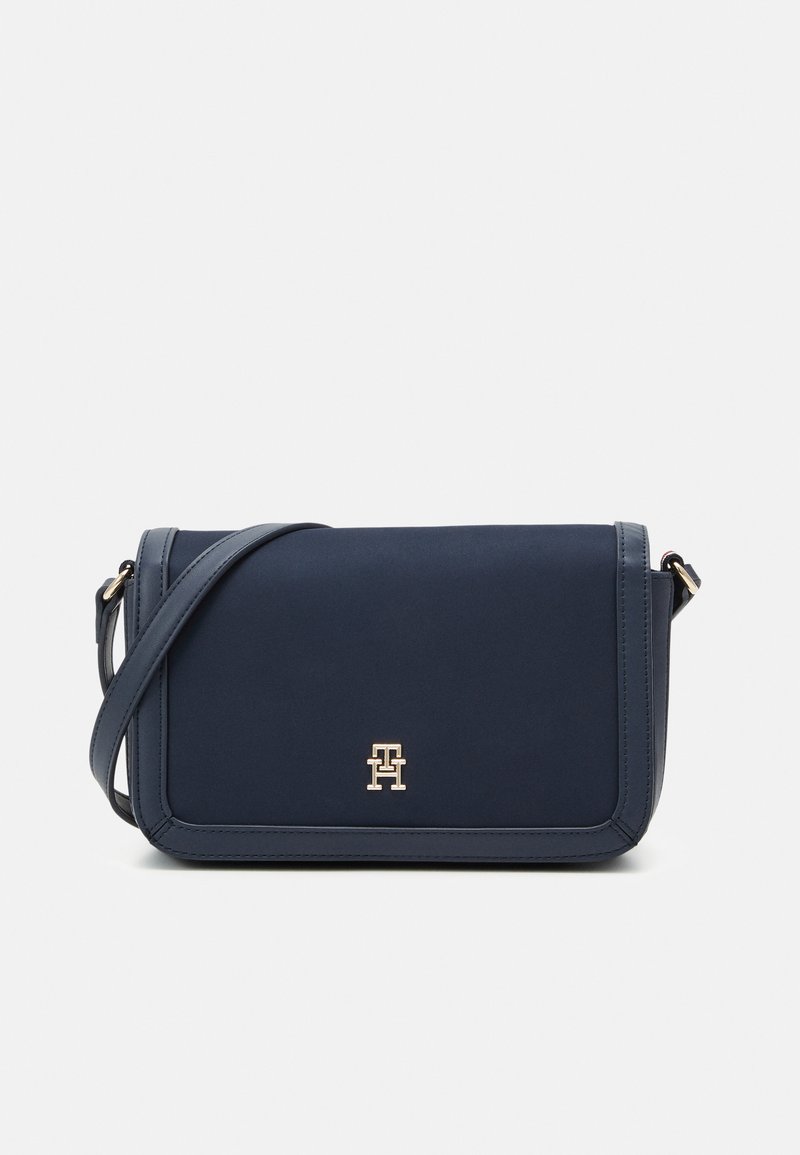 Bolso bandolera azul marino con textura suave, herrajes del logotipo en tono dorado, forma rectangular y correa de hombro ajustable.