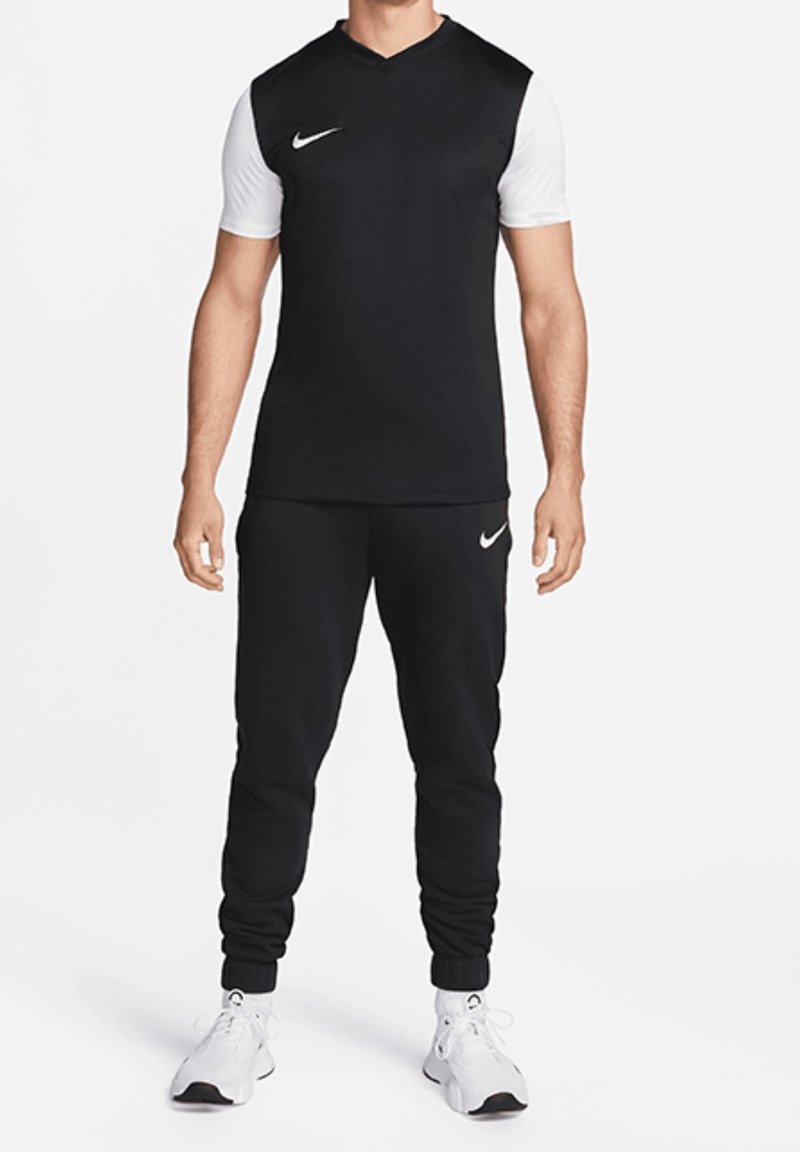 Nike träningskläder som består av en svart kortärmad topp med v-ringning och vita ärmar, tillsammans med svarta joggers. Båda har logotypdetaljer.