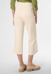 Krémové zkrácené kalhoty s přiléhavým pasem, dvěma zadními kapsami a texturovaným povrchem, doplněné o světle béžové platformové boty.