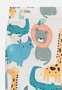 Leggings de algodón con una base blanca y coloridas ilustraciones de varios animales, incluidos un león, una jirafa y un tucán.
