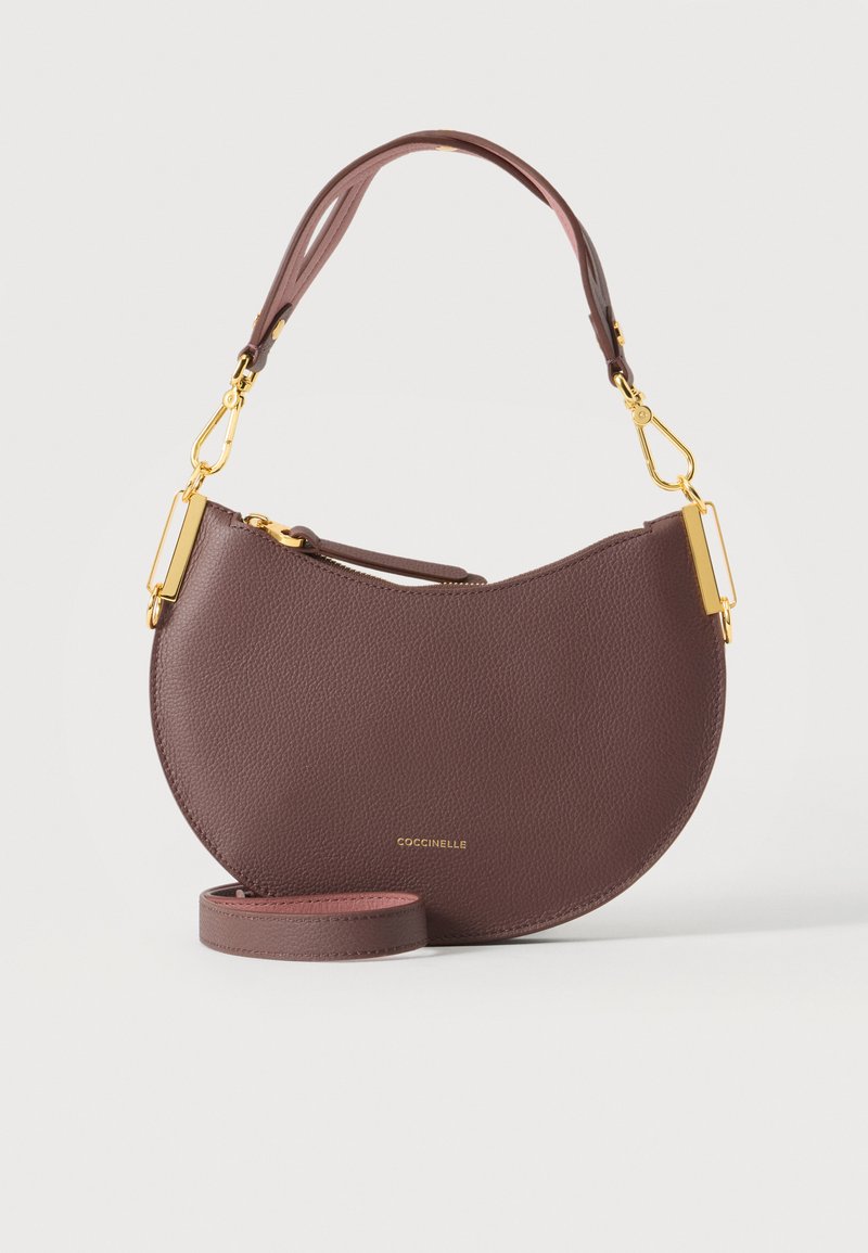 Sac à main en cuir marron demi-lune avec fermoirs dorés, bandoulière détachable et logo "COCCINELLE" au centre avant.