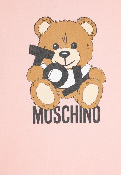 Camiseta rosa com um urso de desenhos animados com textura de pelagem castanha, segurando a palavra "TOY" em fonte preta e bold, com "MOSCHINO" impresso abaixo.
