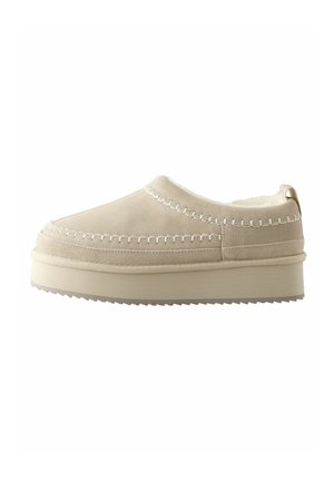 Bež slip-on cipele sa mekanom nubuk kožom, bijelim šavovima i debelim gumenenim đonom s teksturom za prianjanje.
