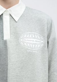 Pilkas ilgomis rankovėmis polo marškinėlis su baltais apykakle, krūtinės srityje su spausdintu logotipo dizainu, pagamintas iš medvilnės mišinio audinio.