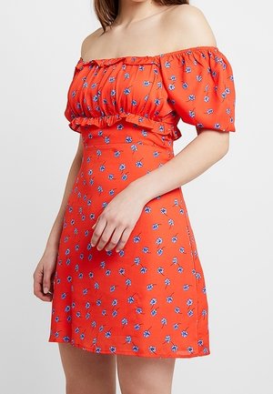Vestido rojo fuera del hombro con mangas abullonadas y cintura ajustada. Presenta pequeños patrones florales azules y un dobladillo con volantes.