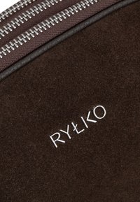 Braune Wildledertasche mit silbernem Reißverschluss, ausgestattet mit geprägtem "RYŁKO"-Logo, glatter Textur und klarer Formgebung.