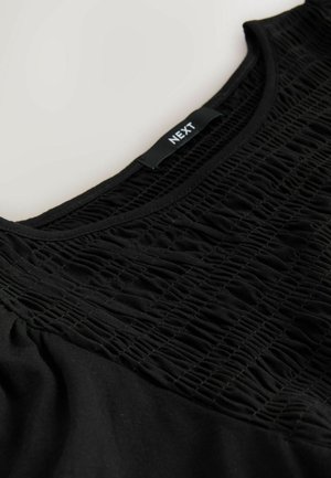 Fekete felső texturált, smock részlettel az elején, sima anyagból és kerek nyakkivágással. A címke felirata: "NEXT."