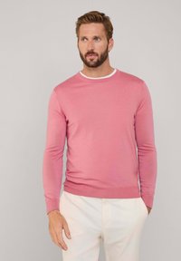 Suéter de punto rosa con cuello redondo, con un ribete blanco en contraste en el cuello y mangas largas de corte ajustado.