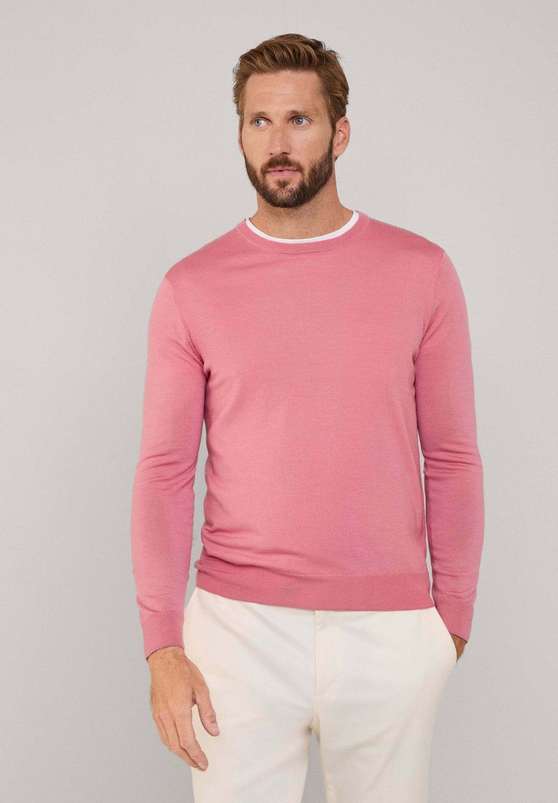 Suéter de punto rosa con cuello redondo, con un ribete blanco en contraste en el cuello y mangas largas de corte ajustado.