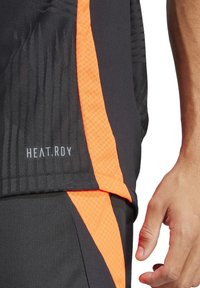 Zwarte sportshorts met een oranje accentstreep. Heeft een gestructureerde stof en het "HEAT.RDY" logo nabij de zoom. Close-up van de zijkant.