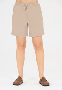 Beige bomullsshorts med elastisk midja och dragsko, med sidofickor och rak passform. Bärs med bruna slip-on skor.