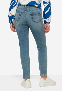 Ljusblå jeans med slim fit, med bakfickor, sydda detaljer och en något blekt textur. Matchade med vita sneakers.