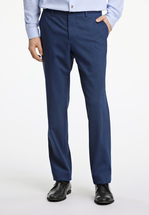 Navyblauwe broeken met een rechte pasvorm, gemaakt van een lichtgewicht stof; beschikt over een strakke uitstraling en twee zijzakken, gecombineerd met zwarte schoenen.