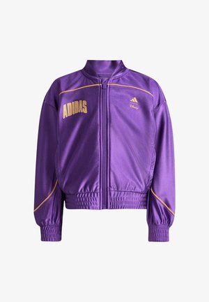 Giacca viola con zip, con loghi gialli Adidas e Disney, dettagli in piping giallo, polsini ed elastico in vita.