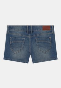 Denim-Shorts in Mittelblau mit einem Fünf-Taschen-Design. Sie verfügen über zwei hintere Taschen mit einer gewellten Form und einem braunen Lederpatch an der Taille.
