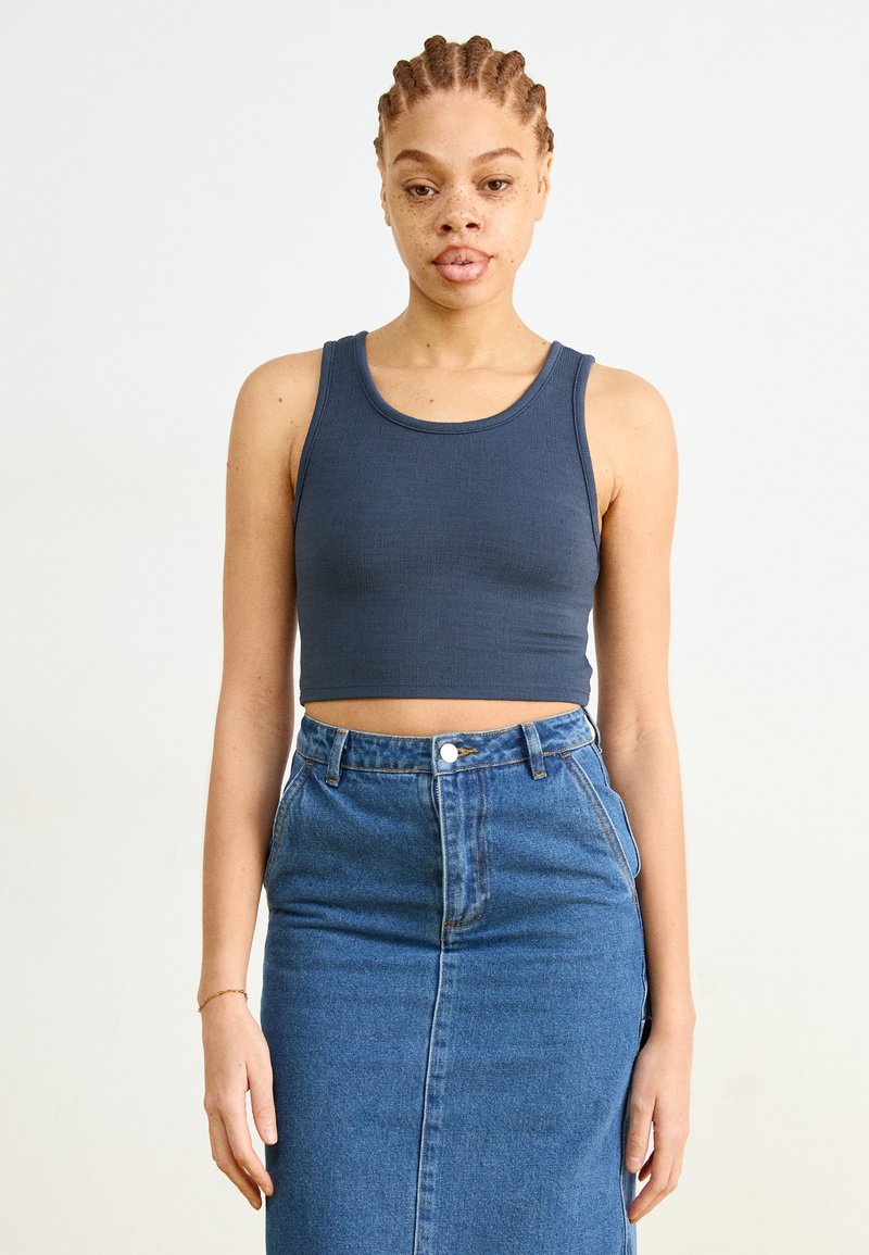 Dark blue ribbed crop top paired with a high-waisted denim skirt. The top features a round neckline and fitted design.