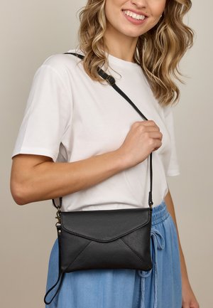 Schwarze Leder-Umhängetasche mit einem Umschlagdesign, strukturiertem Finish, rechteckiger Form und verstellbarem Tragegurt.