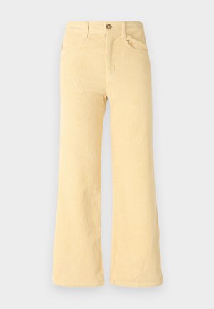 Pantalones de pana amarillos de pierna acampanada con una textura acanalada, que cuentan con cinco bolsillos y un cierre frontal con botón.