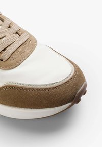 Sneakers z brązowego zamszu i off-white syntetycznego materiału, okrągły czubek, płaskie sznurowadła oraz kontrastowe przeszycie wzdłuż krawędzi.