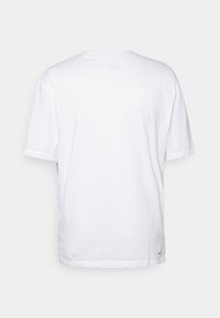 Vit bomullströja med korta ärmar, design med rund hals. Har en enfärgad baksida utan grafik eller mönster, mjuk textur.