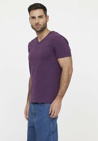 Paarse V-hals t-shirt van zachte stof, met korte mouwen en een slim fit ontwerp. Kleine logodetail op de borst. Gecombineerd met blauwe jeans.