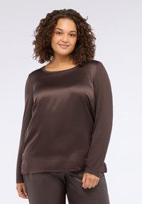 Top marrone a maniche lunghe realizzato in tessuto liscio e lucido, con scollatura a girocollo e vestibilità rilassata, abbinato a pantaloni marroni coordinati.