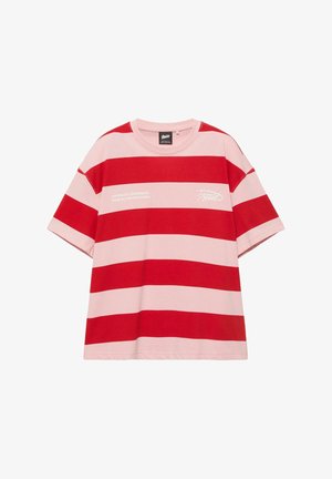 Majica s kratkim rukavima, širokim horizontalnim crvenim i ružičastim prugama, okruglim izrezom i bijelim tekstom na prsima koji glasi "UJEDINJUJUĆI SVE POKRETE IZ SVIH POZADINA."