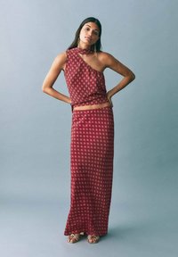 Bordo dvodelni komplet, ki vključuje enostranski crop top s cvetličnim vzorcem in ujemajočo dolgo krilo, oba iz lahkega blaga z gladko teksturo.