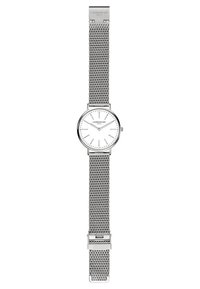 Montre à bracelet en maille argentée avec un cadran rond blanc. Elle présente des index et des aiguilles fins, avec une fermeture à clip et un gravage de la marque sur le bracelet.