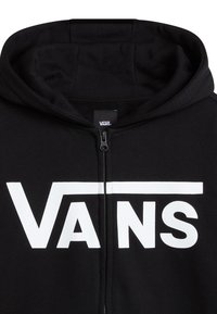 Zwarte ritsen-hoody met een groot wit "VANS" logo op de voorkant, voorzien van een capuchon met trekkoord en een zachte stofstructuur.