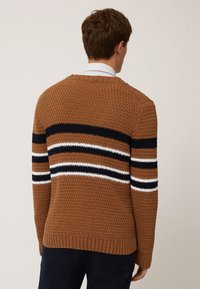 Brun stickad tröja med horisontella ränder i marinblått, vitt och orange. Har ett strukturerat mönster och ribbade muddar och nederkant.