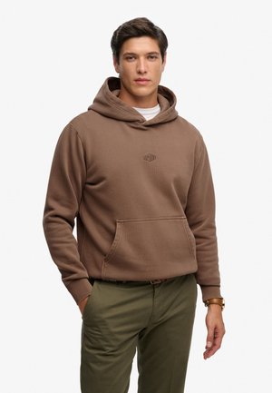 Felpa marrone con cappuccio e tasca a marsupio, con un piccolo logo sul petto, realizzata in tessuto morbido, abbinata a pantaloni verde oliva.