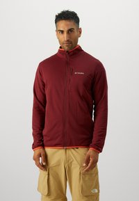 Maroon fleece jacket with a high collar, orange accents, and a zippered pocket. Features a smooth texture and fitted sleeves.