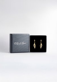 Orecchini a forma di foglia d'oro, presentati in una scatola nera foderata di velluto, con il nome del marchio "Sofia Milani Jewels" impresso sul coperchio.