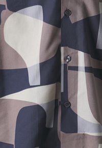 Napapaita jossa on monivärinen abstrakti kuvio navynsinisellä, beige- ja taupe-värillä. Valmistettu kevyestä kankaasta.