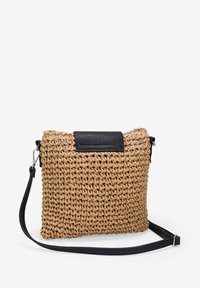 Bolso de paja trenzada tipo bandolera con una solapa de cuero negro, forma rectangular, superficie texturizada y correa ajustable.