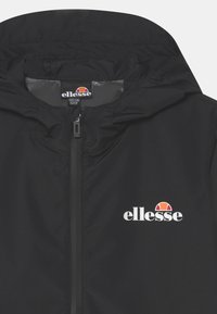 Giacca a zip nera con cappuccio, logo ellesse bianco e arancione sul petto e etichetta della taglia all'interno del colletto.